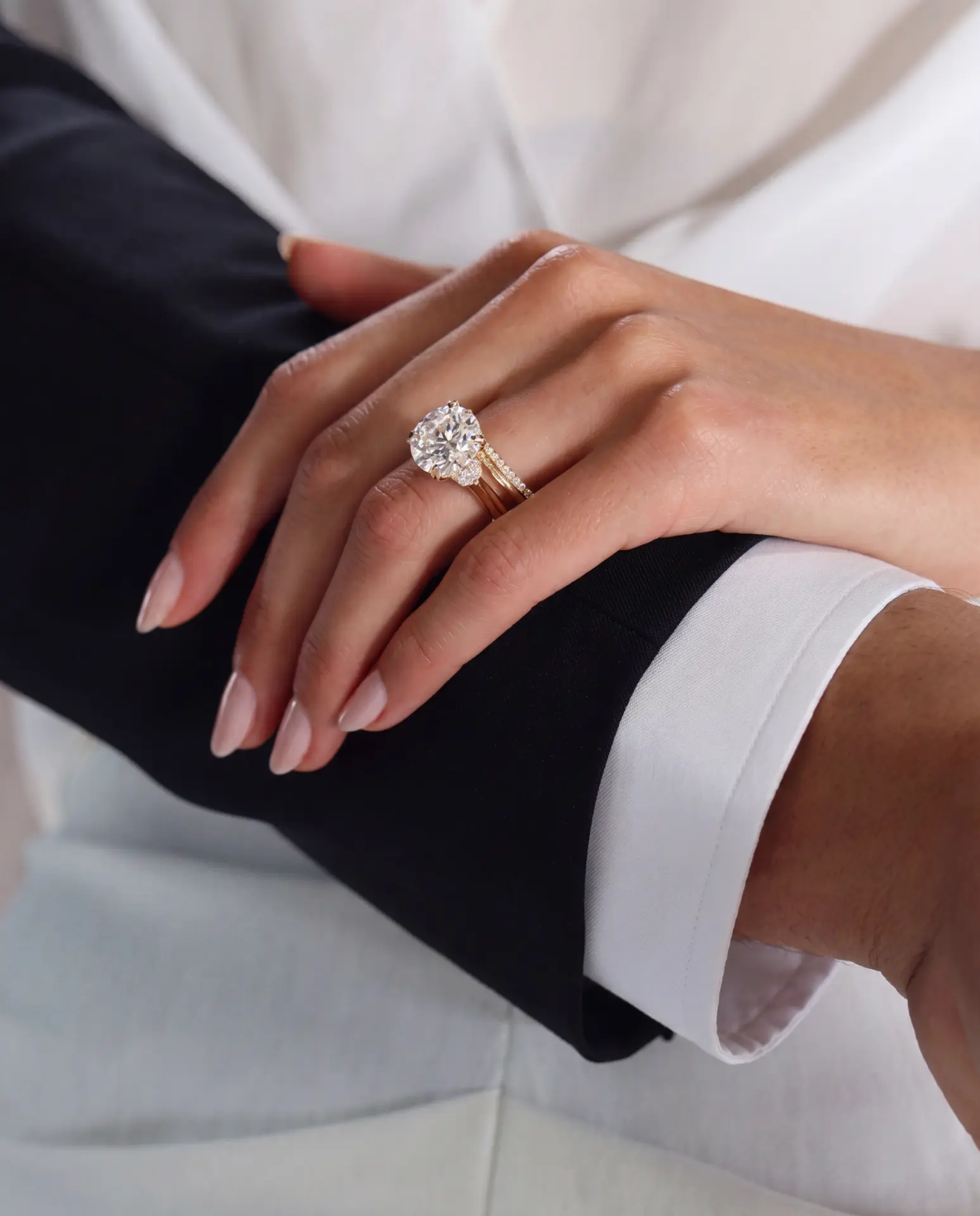 A hand wearing a solitaire ring and diamond band