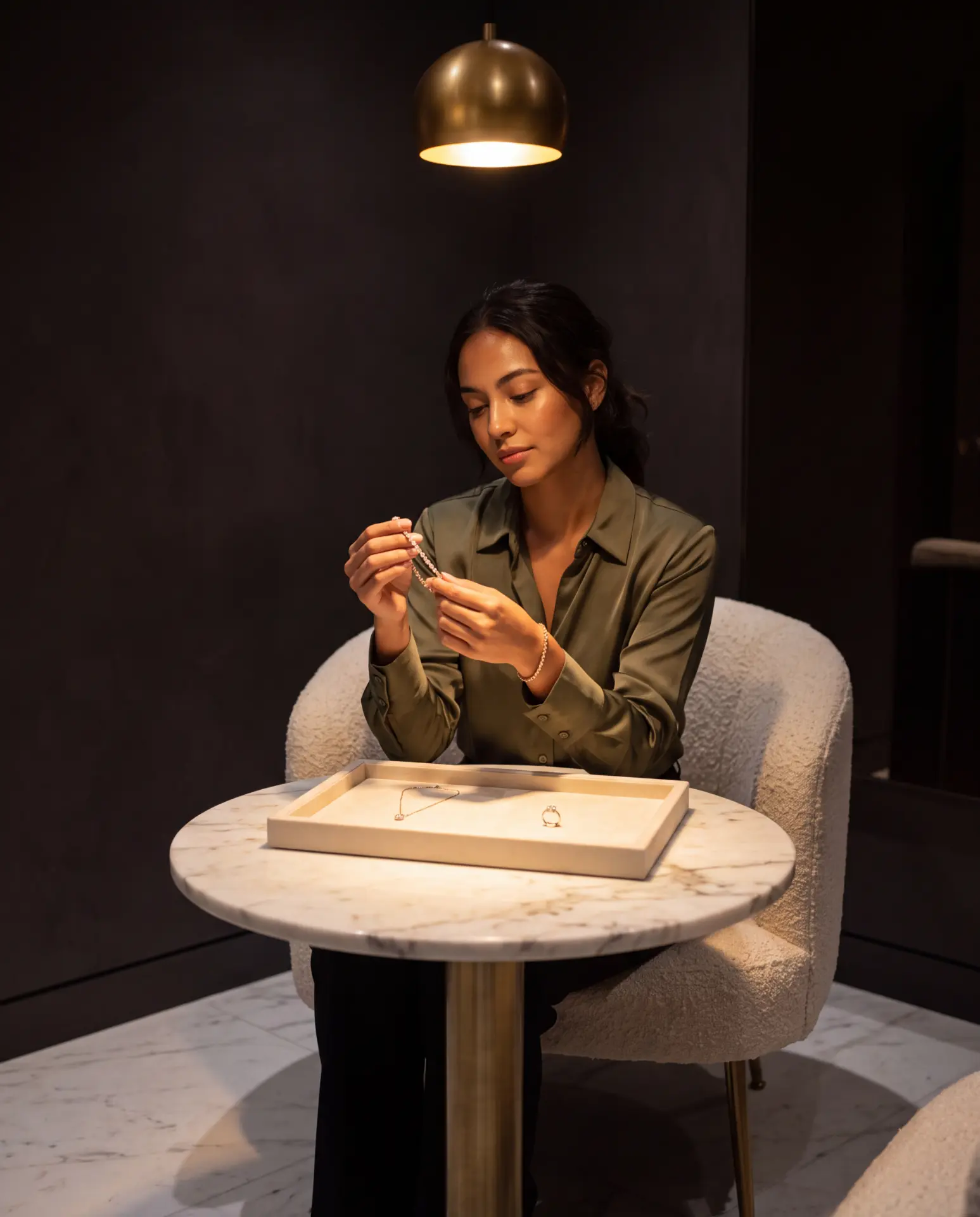 A woman studying a crafted diamond bracelet at a private salon table