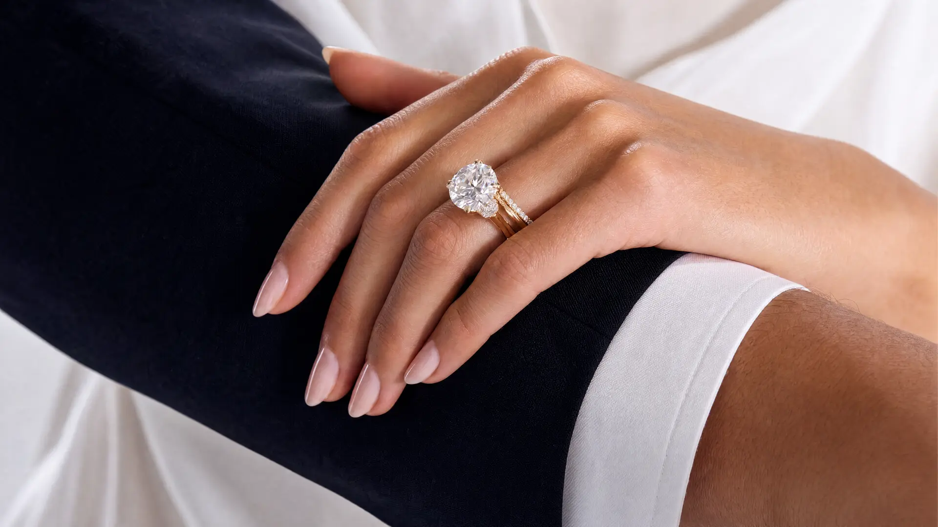 A hand wearing a bespoke round brilliant diamond ring in yellow gold