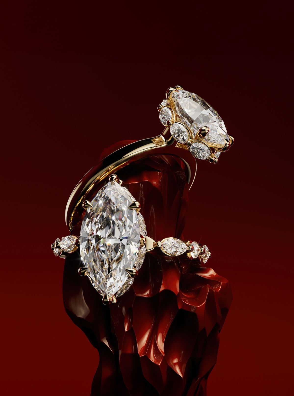 Marquise and pear cut diamond rings in yellow gold on a deep red sculpted form